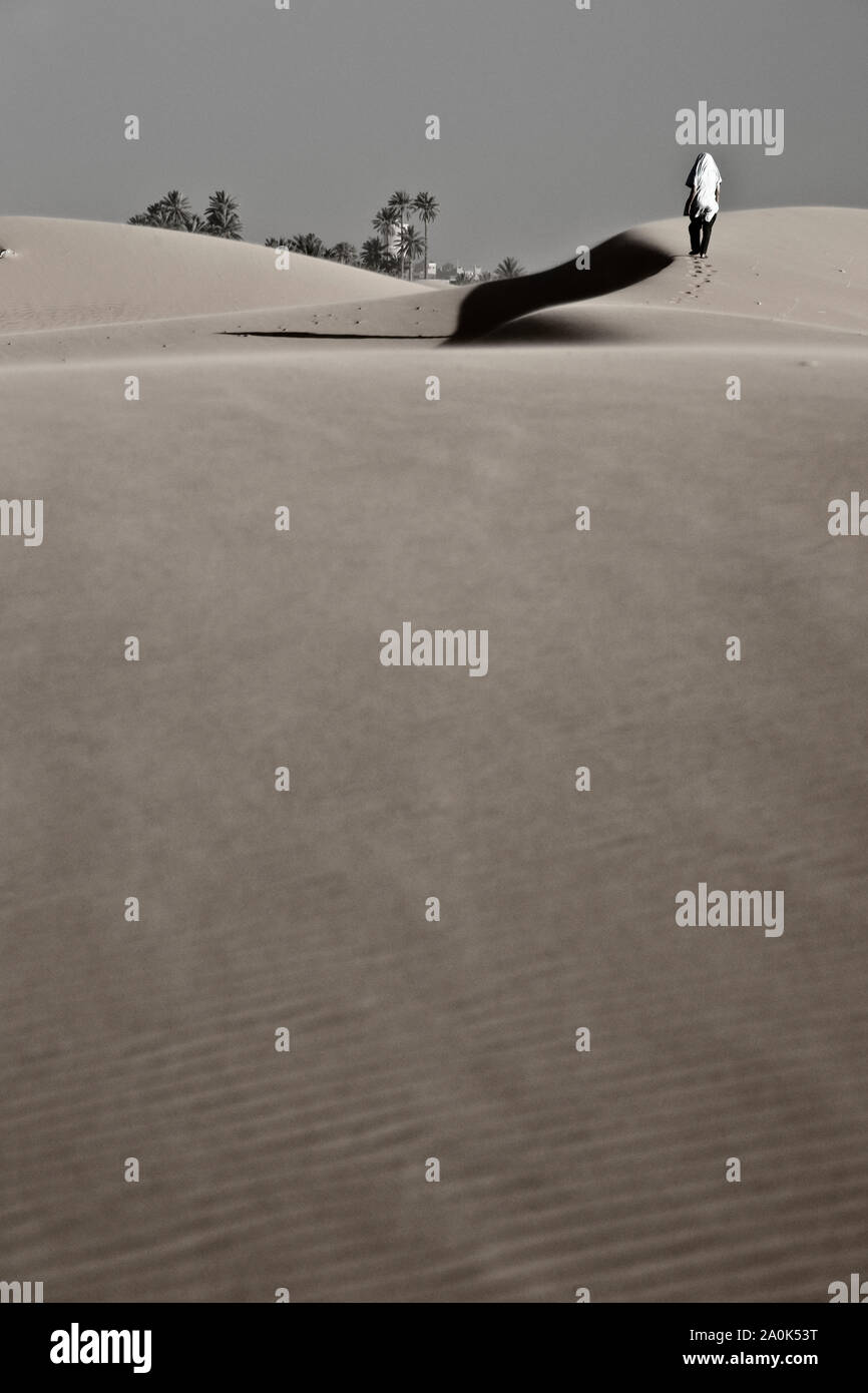 Marokkanischen Mann in seinem 20er klettert ein hohes rippled Sanddüne in der Wüste Sahara; in der Nähe von Fes, Marokko, Afrika Stockfoto