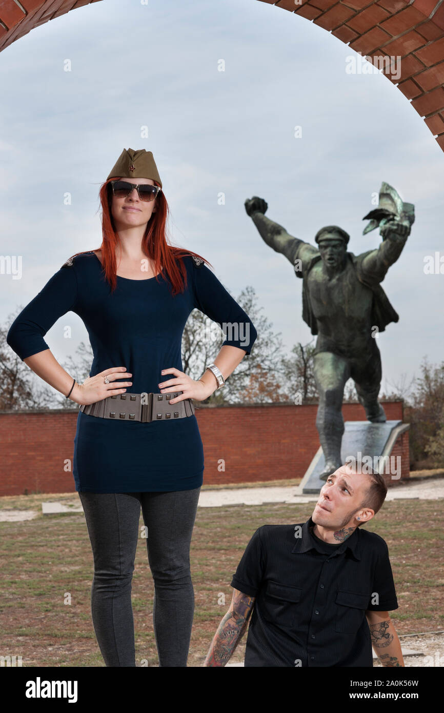 Rothaarige Frau mit Hut und ein Soldat einen tätowierten Mann in seinen 20 visits Sozialistischen diktatorischen Zahlen und Gedenkstätten an Memento Park der Statuen, Bud Stockfoto