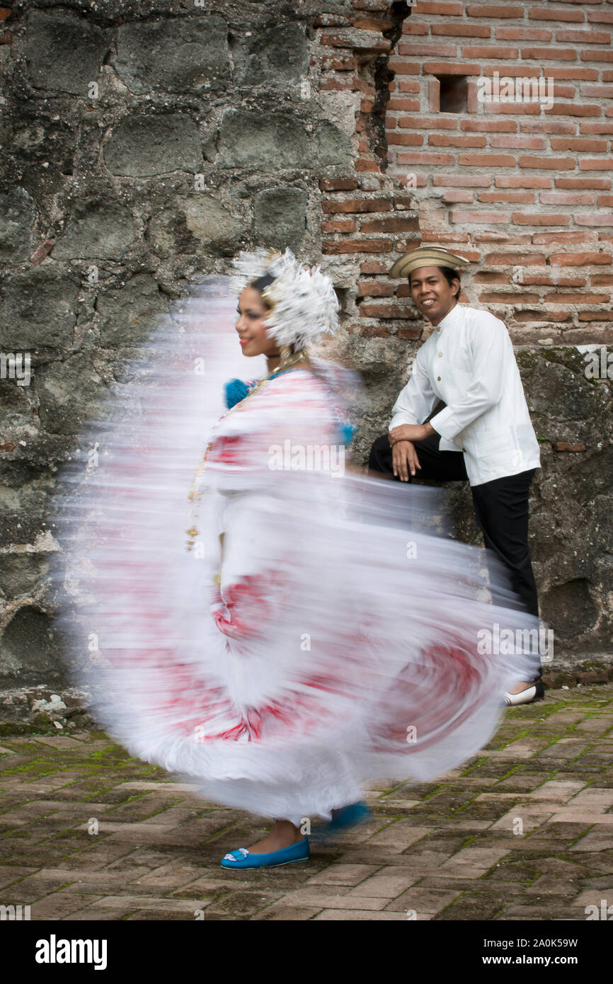 Panamasche Frau bekleidet Pollera, in Panama Tracht, Tänze, während ein Mann mit einem traditionellen mole Uhren zu Panama la Vieja Ruinen, Panama Stockfoto