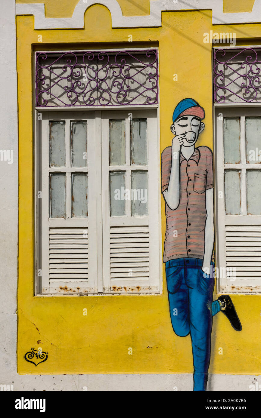 Graffiti des jungen Mannes, Kaffee trinken auf der Colonial gelbes Haus Wand Stockfoto