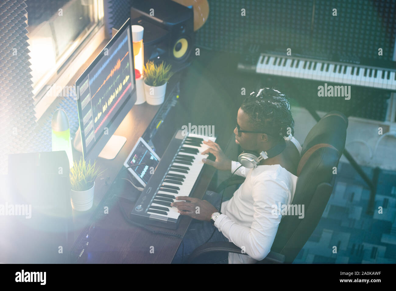 Junge afrikanische Musiker in Freizeitmode am Bildschirm auf der Suche nach Arbeitsplatz Stockfoto