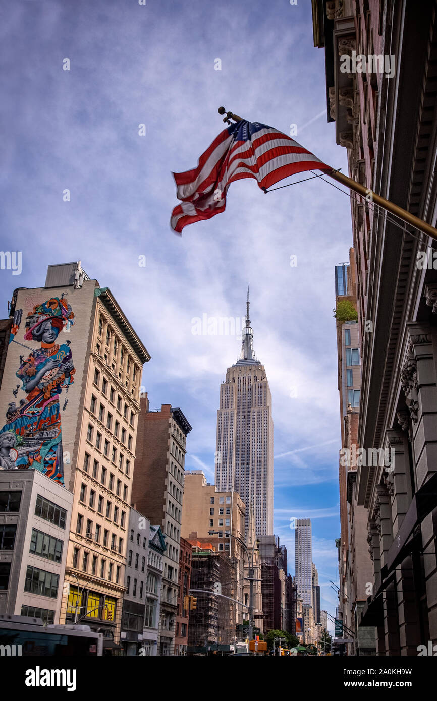 New York Cirt, USA - 31. August 2019: das Empire State Building und die umliegenden Gebäude in Midtown Manhattan mit der USA-Flagge auf der Oberseite Stockfoto
