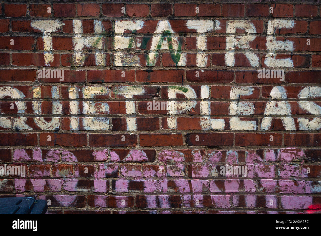 Verblasstes gemaltes Schild an einer roten Ziegelwand, das THEATER RUHIG, mit abgetragenen Schriften und unvollständigen Wörtern darunter liest Stockfoto