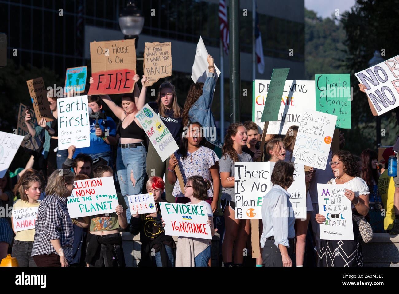 Die Demonstranten halten Schilder auf vorbeifahrende Autos auf internationaler Klimagerechtigkeit Rallye in Asheville, NC, USA. Stockfoto