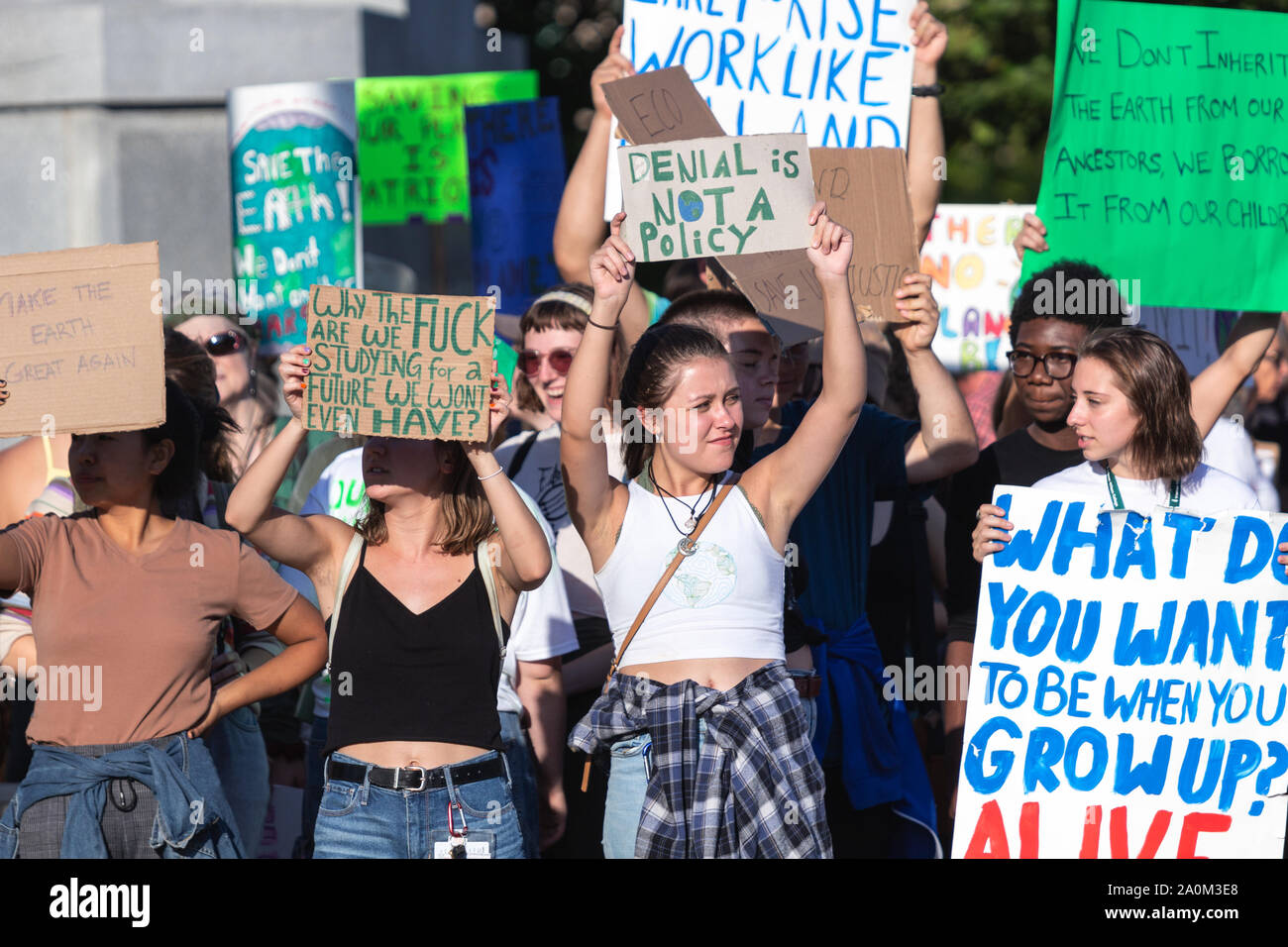 Die Demonstranten halten Schilder auf vorbeifahrende Autos auf internationaler Klimagerechtigkeit Rallye in Asheville, NC, USA. Stockfoto