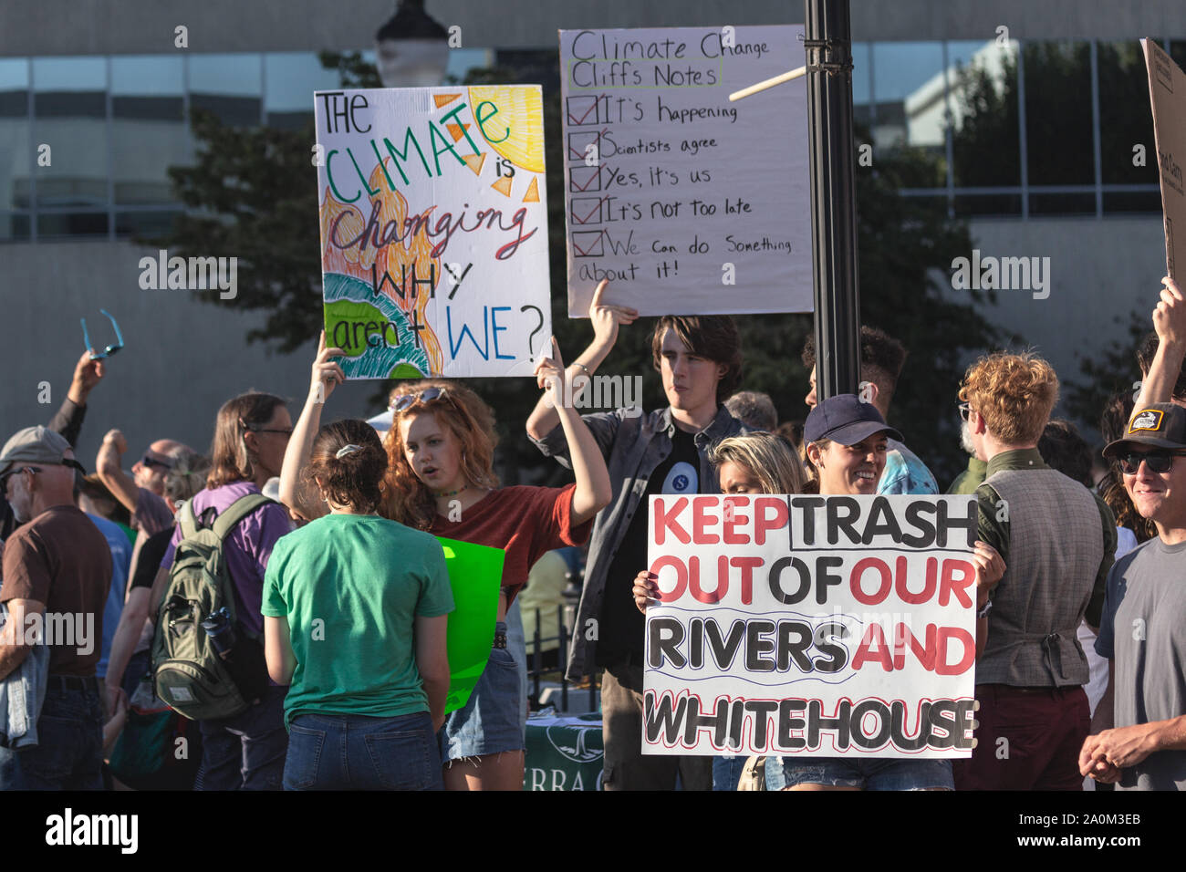 Die Demonstranten halten Schilder auf vorbeifahrende Autos auf internationaler Klimagerechtigkeit Rallye in Asheville, NC, USA. Stockfoto