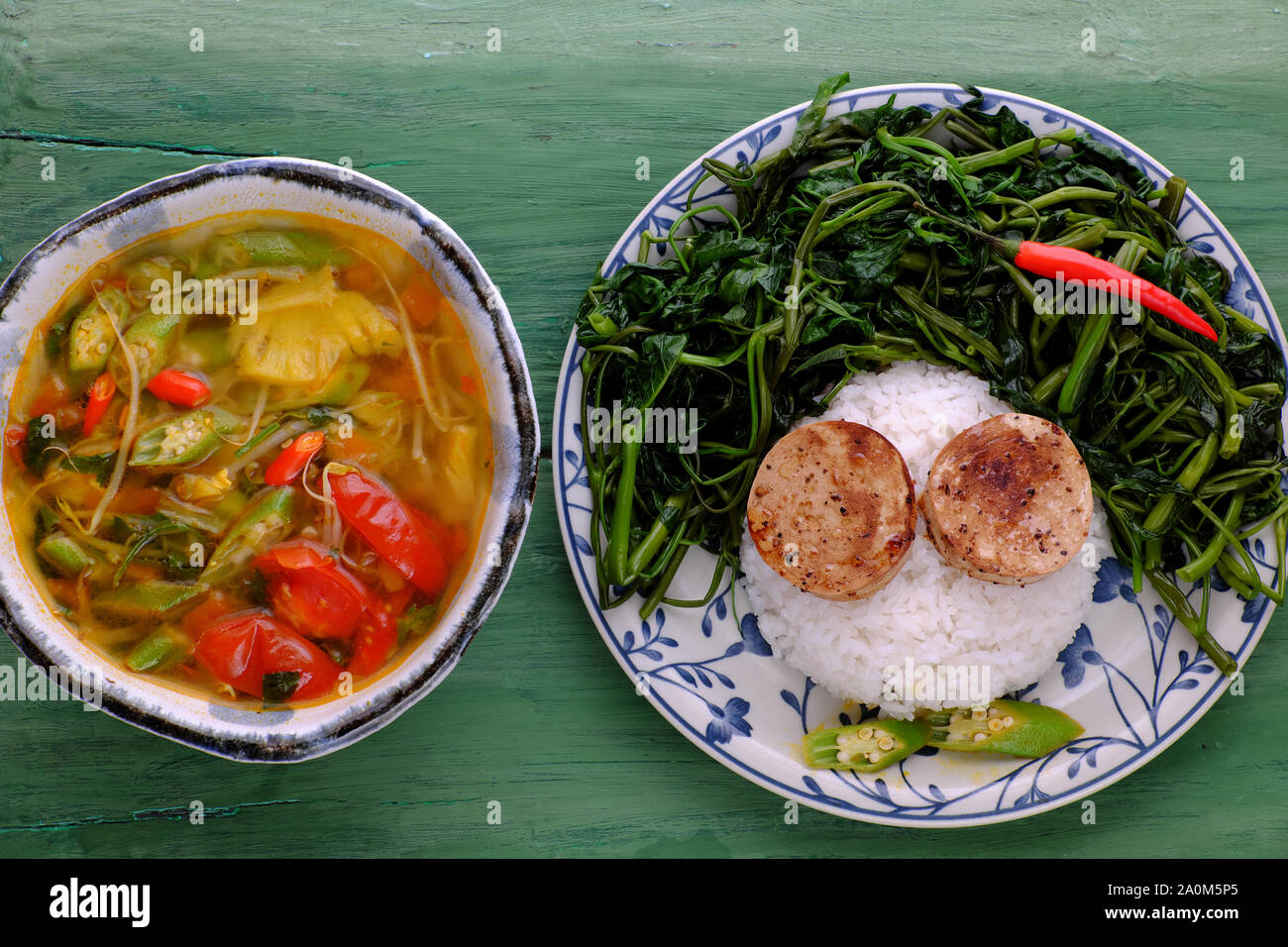 Teller mit Reisgericht, gekochtes Wasser Morgen Ruhm, vegane Wurst kochen mit Sauce, saure Suppenschüssel aus Tomaten, Okra, Ananas, Ernährung vegetarische Mahlzeit Stockfoto