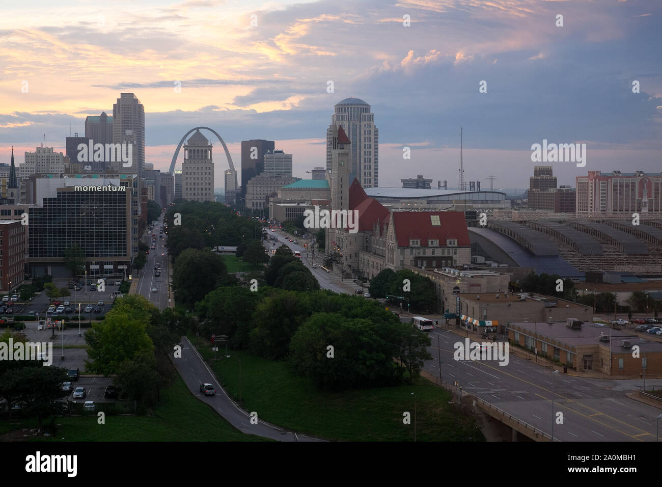 Der Gateway Arch erhebt sich bei Sonnenaufgang über der Skyline von St Louis, wobei das historische Gebäude der Union Station im Vordergrund steht. Stockfoto