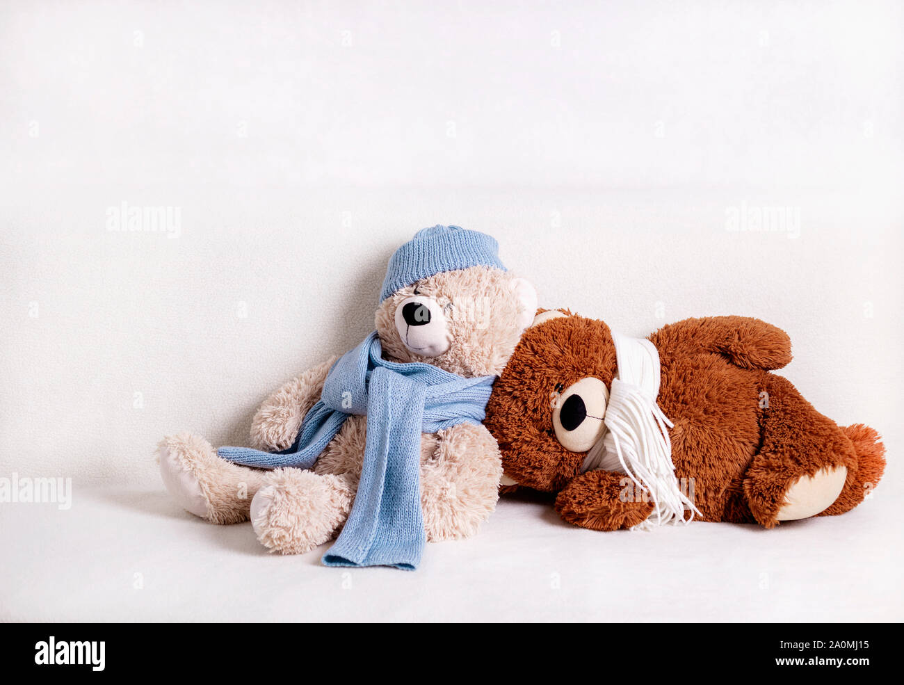 Kinder Spielzeug Teddybären sitzen auf einem weißen Sofa in einem gestrickt, weißen und blauen Schal und Hut. Selektive konzentrieren. Stockfoto