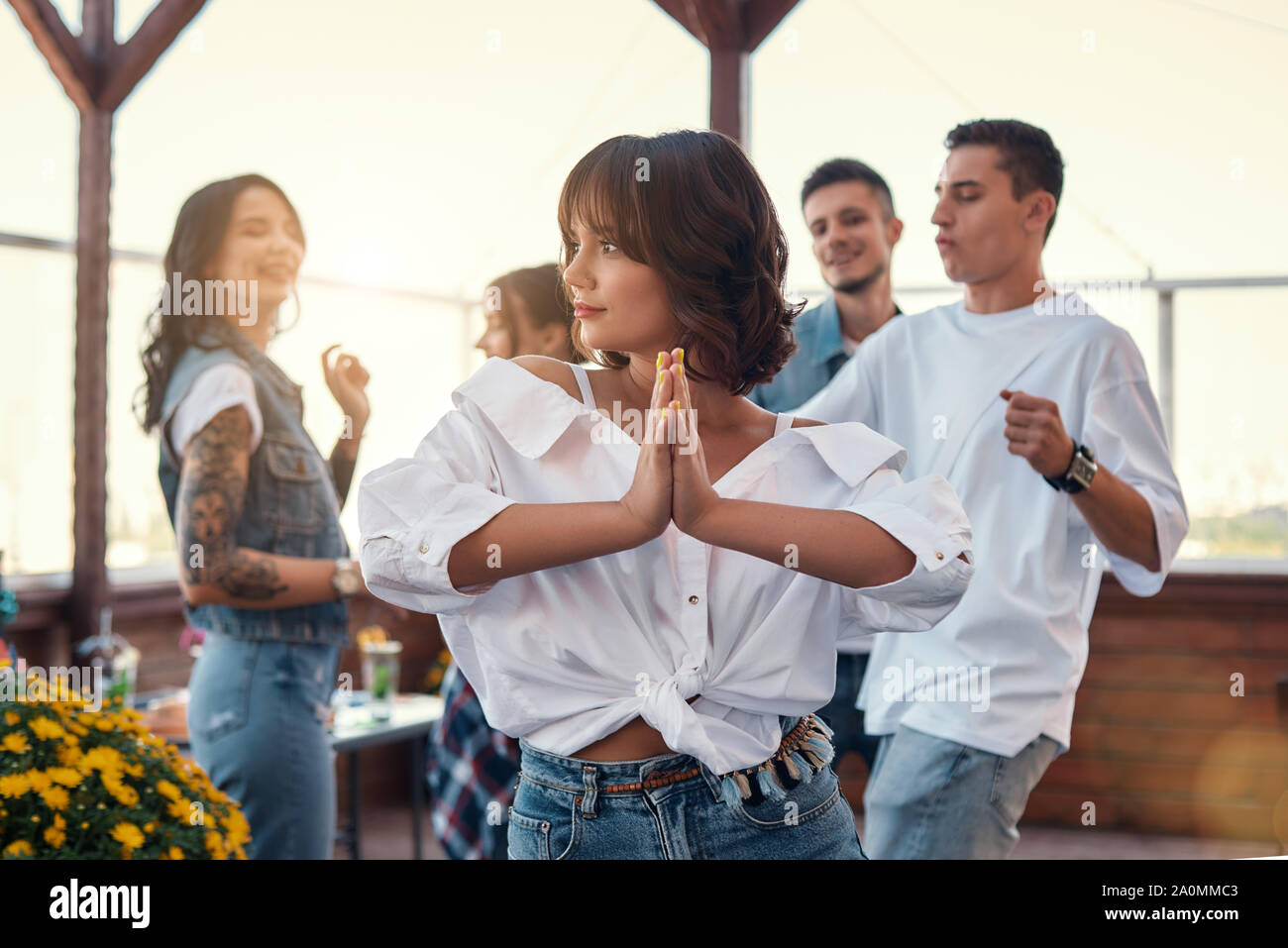 Gefühl glücklich und friedlich. Hübsche und junge Frau im weißen Hemd mit Handflächen zusammen und genießen Sie auf der Dachterrasse mit Freunden. Geburtstag Konzept. Freundschaft Stockfoto