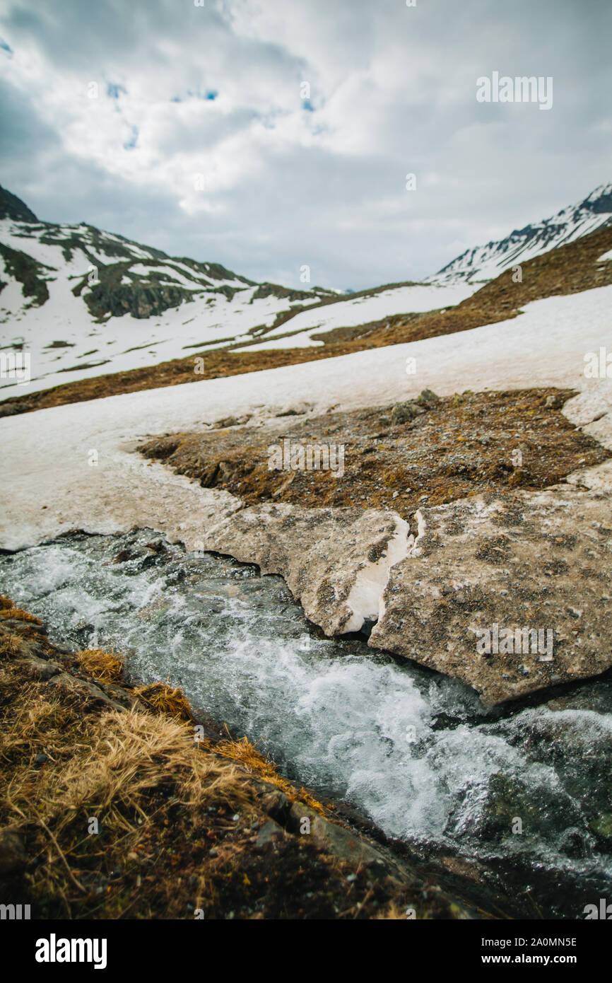 Der Schneeschmelze in den Bergen und fließt in den Creek, in der Nähe. Der detaillierte Blick auf Wasser läuft unter Eis in einem Fluss. Stockfoto