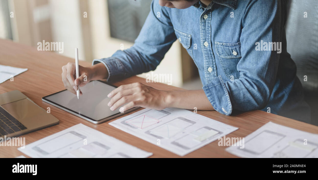 7/8-Ansicht von UX Web Developer zeichnen das Smartphone Vorlagen auf Tablet in modernen Büro Zimmer Stockfoto