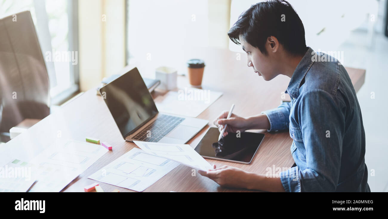 7/8-Ansicht von UX Web Developer zeichnen das Smartphone Vorlagen auf Tablet in modernen Büro Zimmer Stockfoto