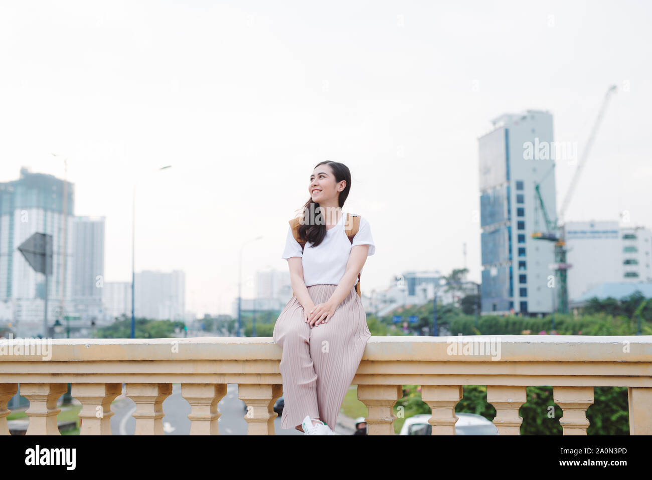 Lebensstil im Freien Nahaufnahme Portrait von glückliche junge Frau in stilvollen casual Outfit sitzt auf der Brücke auf der Straße. Ziemlich hipster Mädchen Spaß und Stockfoto