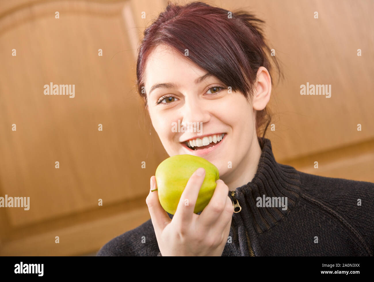 Junge Frau isst einen Apfel im Innenbereich Stockfoto