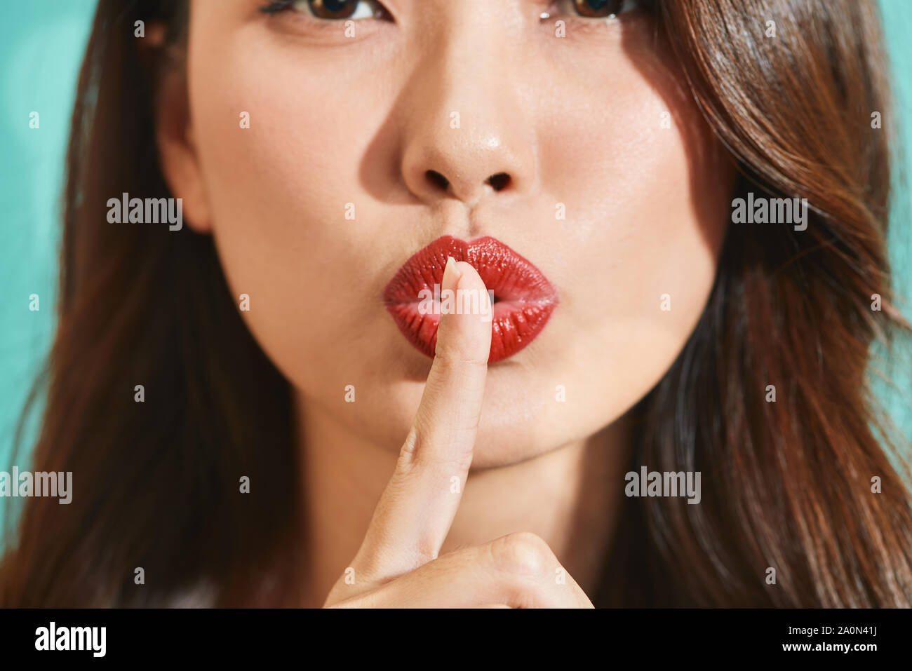 Asiatische Frau mit Zeigefinger auf die Lippen, bitten ruhig zu sein. Stille und heimliche Konzept Stockfoto