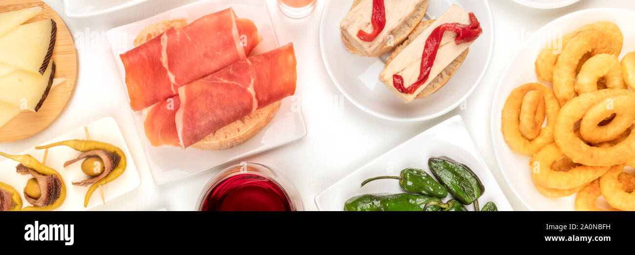 Ein Panorama von spanischen Tapas. Jamon, Tintenfischringe, Käse, gildas und andere Snacks, Schuß von oben auf weißem Hintergrund Stockfoto