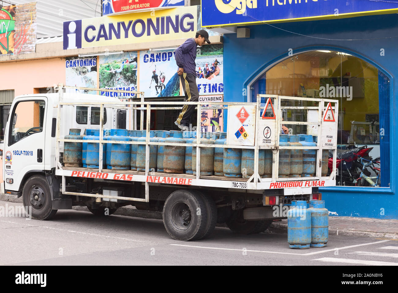 BANOS, Ecuador - 28. FEBRUAR 2014: Nicht identifizierte Person auf einem Lkw voll Gas Flaschen auf der 16 de November Straße in Baños, Ecuador Stockfoto