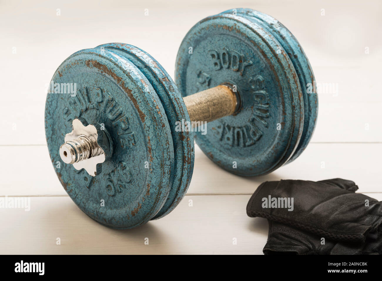 Eine Hantel und Handschuhe auf weißem Hintergrund bestiegen. Stockfoto