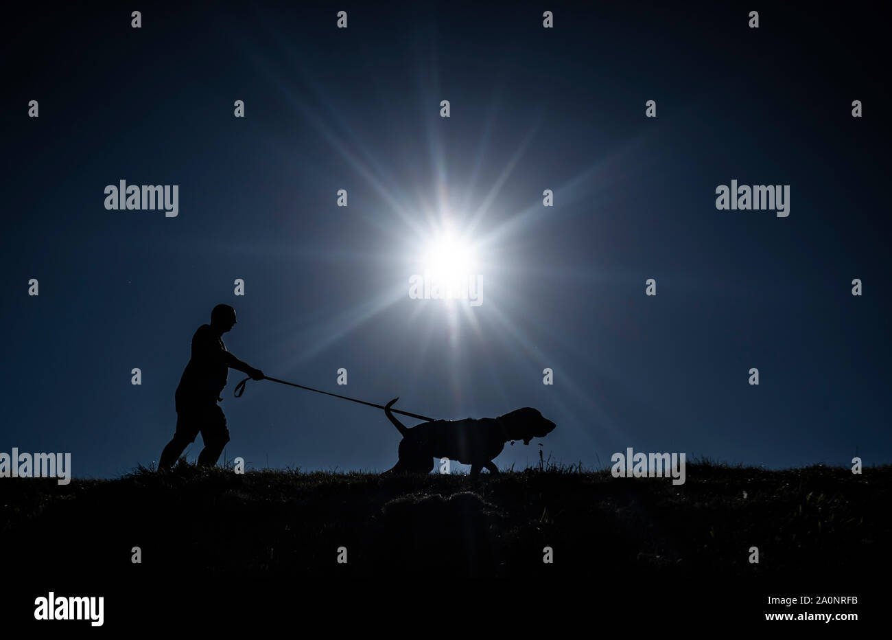 Ein Mann wird gegen die Sonne Silhouette als geht er seinen Hund in Whitby, Yorkshire, wie Temperaturen erwartet werden in einigen Teilen des Landes an diesem Wochenende 26 C zu erheben. Stockfoto