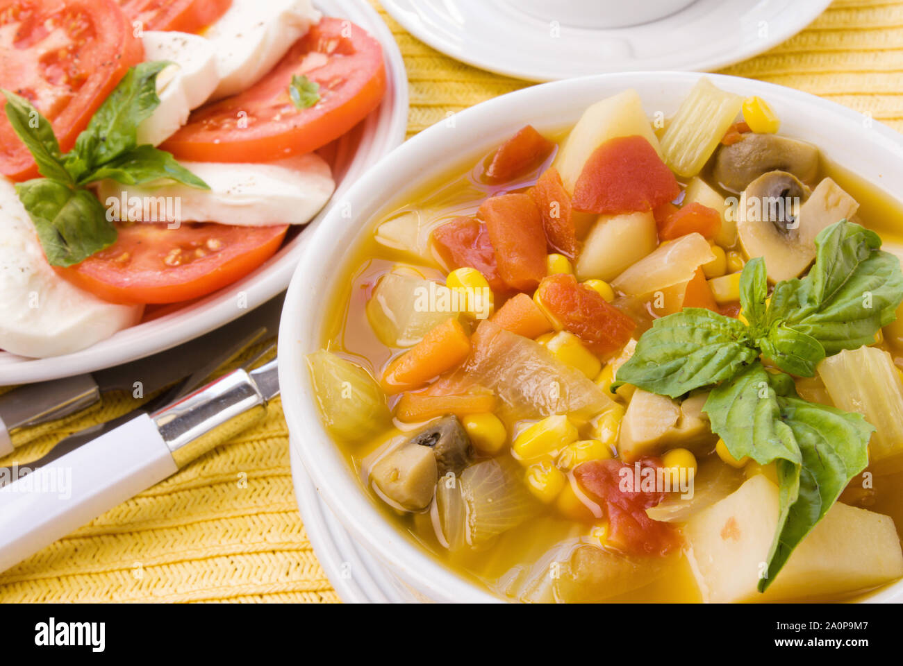 Hausgemachte Gemüsesuppe serviert italienische Küche mit einer klassischen Salat mit roten Tomaten und grüne Basilikum und weißen Mozzarella Käse gemacht. Stockfoto