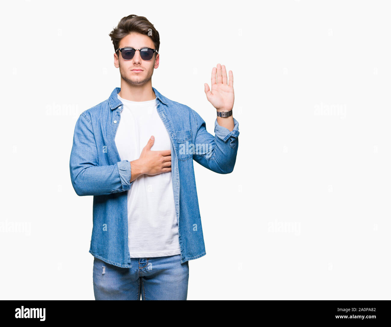 Jungen gutaussehenden Mann Sonnenbrille tragen über isolierte Hintergrund Vereidigung mit der Hand auf der Brust und öffnen Sie Palm, die eine Treue versprechen, Eid Stockfoto