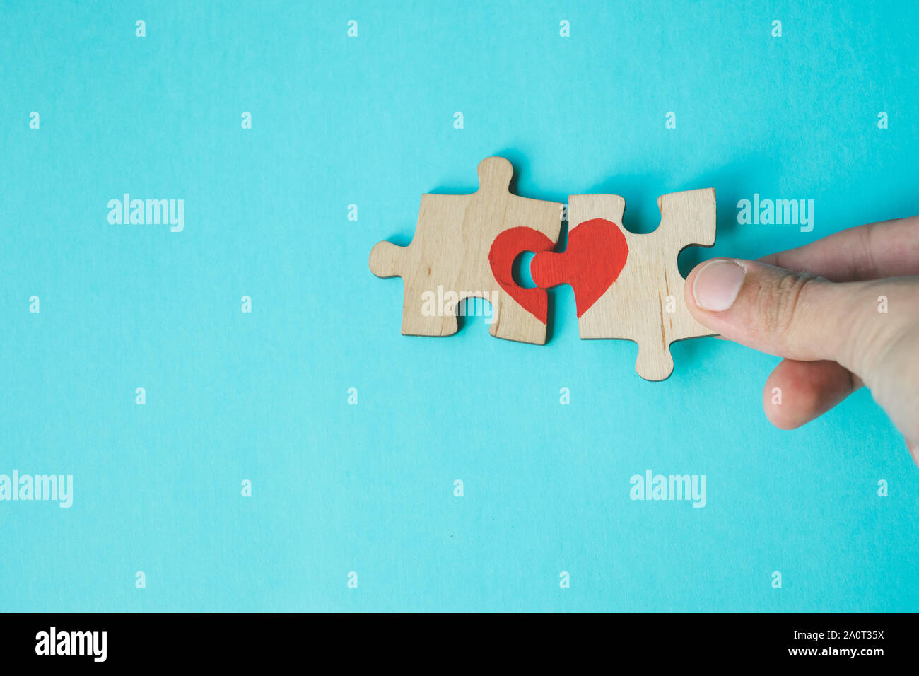 Weibliche Hand verbinden Puzzle mit roten Herzen auf blauem Hintergrund. Liebe Konzept. St. Valentinstag. Versöhnung. Reunion Konzept. Kopieren Sie Platz. Stockfoto