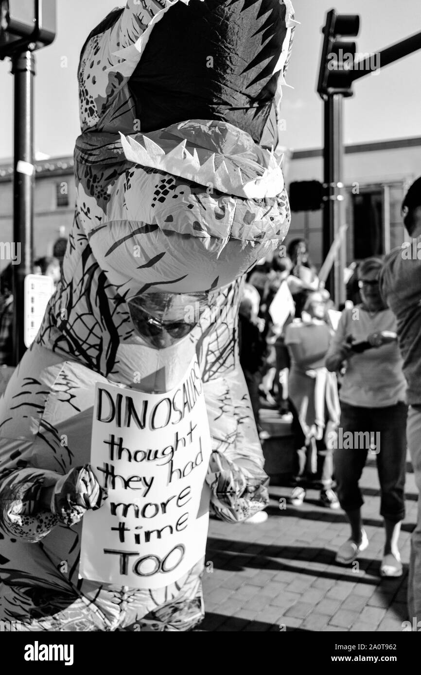 Ein Protestler, der ein Dinosaurier-Kostüm trägt, hält ein Schild bei der International Climate Justice Rally in Asheville, NC, USA. Stockfoto