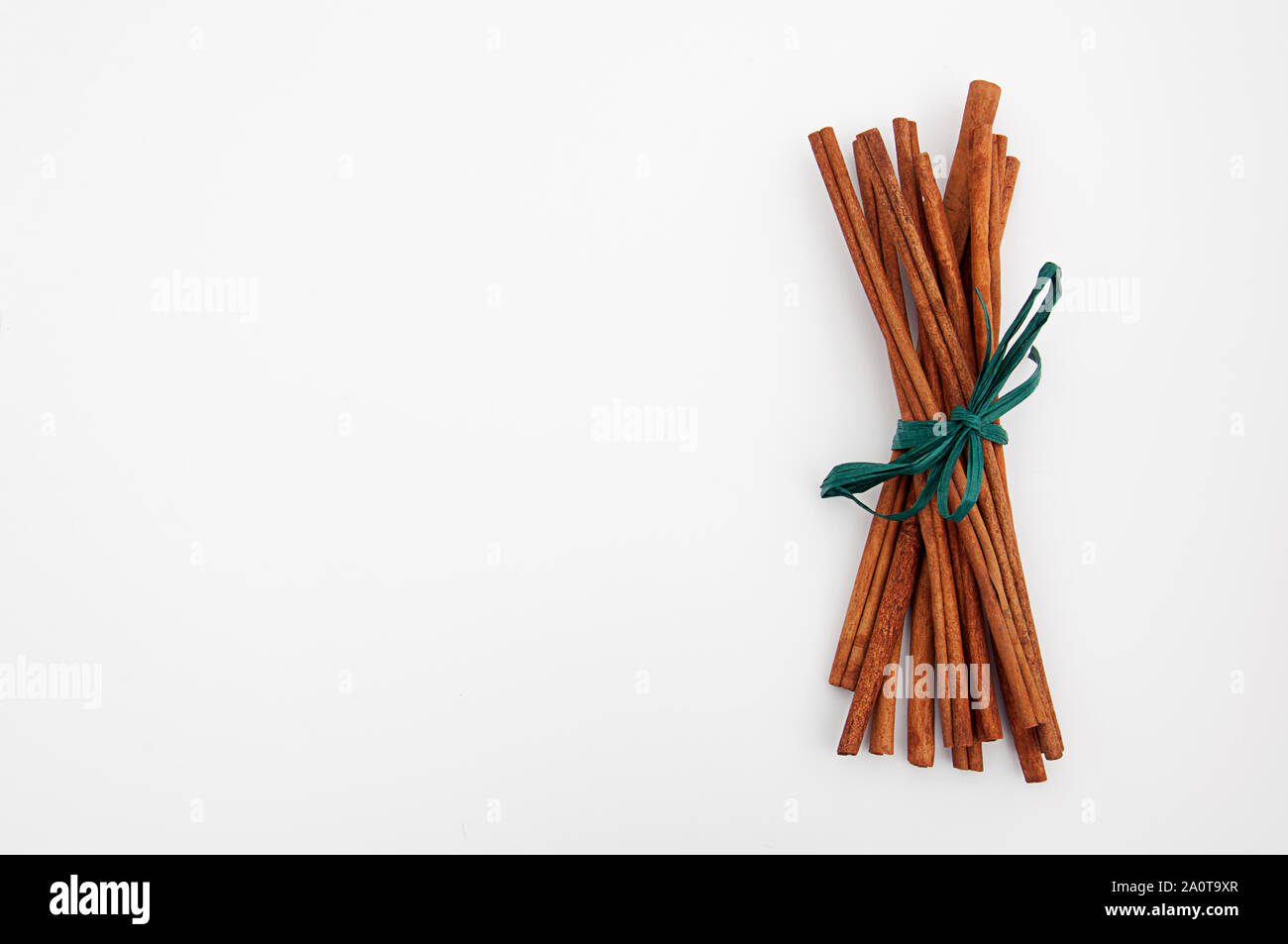 Cinnamon Sticks mit grüner Bast ribbon noch Leben auf hellen Hintergrund mit viel Platz für benutzerdefinierte Text isoliert. Stockfoto