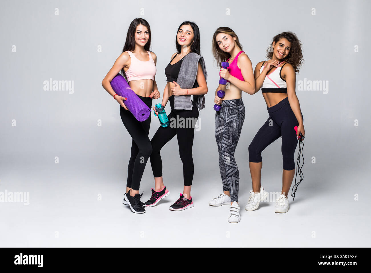 Gruppenporträt junger sportlich begeistert schöne Mädchen mit übung Ausrüstung neben weißen Wand lachen und miteinander reden. Candid funny Stockfoto