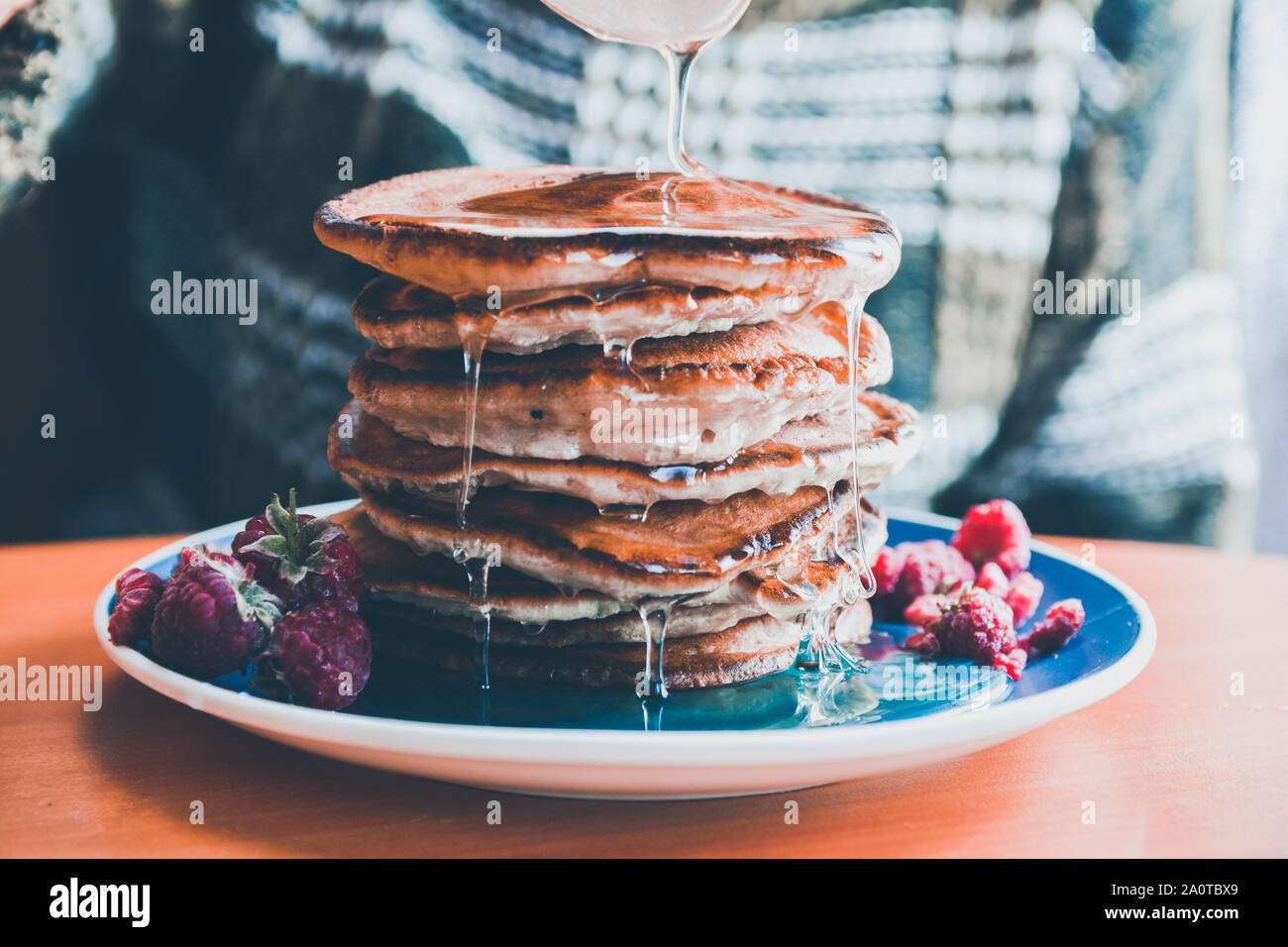 Pfannkuchen mit Tropfen Honig auf einem blauen Schild mit Himbeeren. Stockfoto