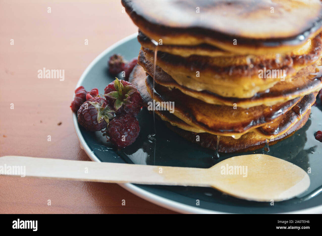 Pfannkuchen mit Tropfen Honig auf einem blauen Schild mit Himbeeren. Stockfoto