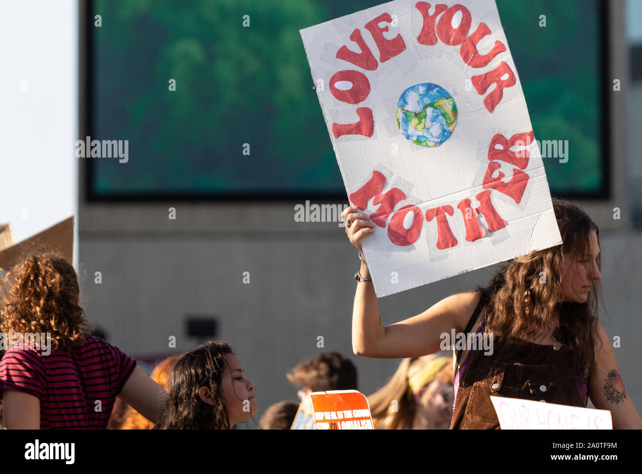 Ein tausendjähriges Mädchen hält ein Zeichen, das "Love Your Mother" bei der International Climate Justice Rally in Asheville, NC, USA sagt Stockfoto