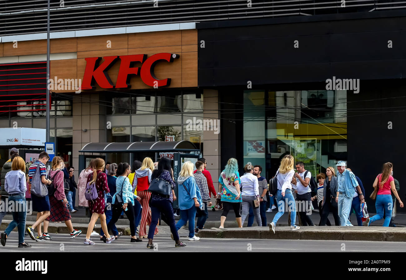Bukarest, Rumänien - 19. September 2019: Viele Frauen in bunten Kleidern gekleidet, überqueren Sie die Straße in der Nähe von KFC Restaurant vom Erdgeschoss von Uni Stockfoto