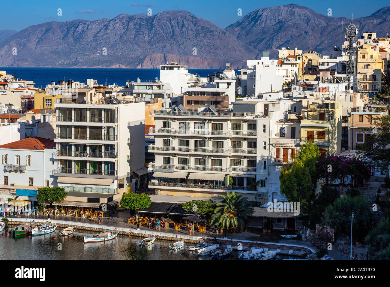 AGIOS NIKOLAOS, KRETA, GRIECHENLAND: 12. September 2019: See Voulismeni und verschiedenen bunten Gebäude in Agios Nikolaos bei Sonnenuntergang gesehen, Osten der Insel Kreta, Griechenland Stockfoto