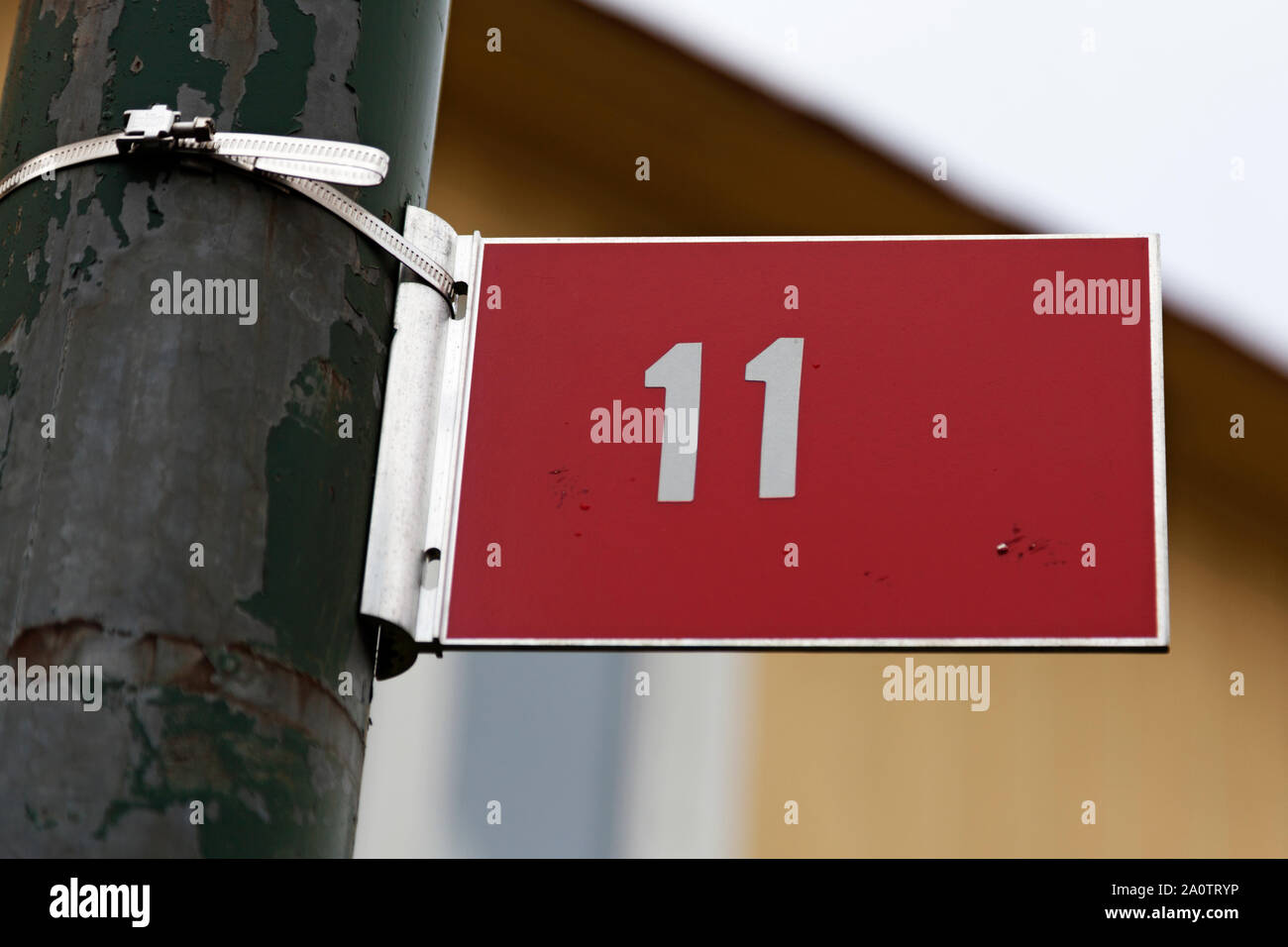 Die Ziffer 11 auf einem roten Metall Schild mit weißem Text, das Zeichen auf einem grünen rusty Lamp Post klemmt Stockfoto