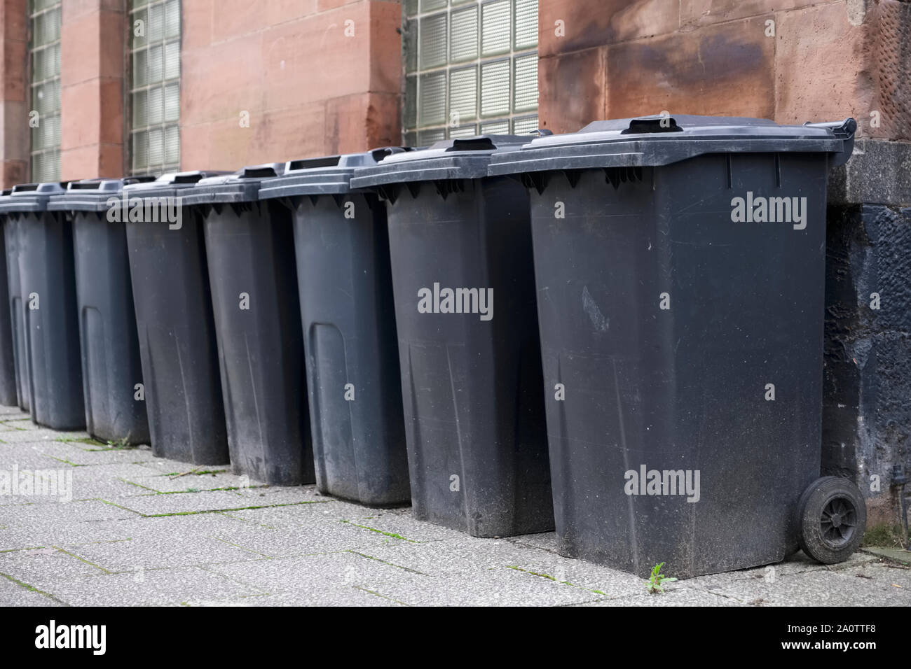 Schwarz wheelie Bins in einer Zeile auf Straßen mit Hausnummern auf der Vorderseite gedruckt Warten bin Männer zu sammeln Stockfoto