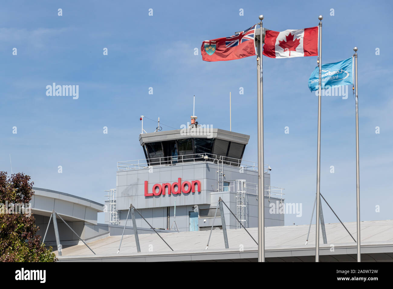 London International Airport, Air Traffic Control Tower über Terminal mit "London" Zeichen und Fahnen schwenkten vor. Stockfoto