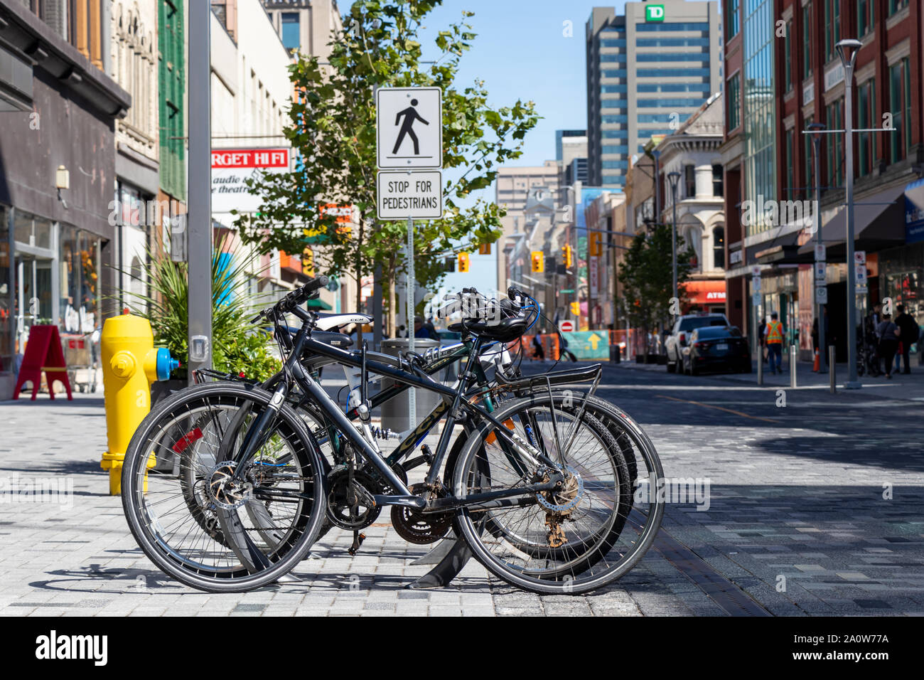 Fahrräder gefesselt auf der Bike Rack in der Innenstadt von London, Ontario mit hinter einer Fußgängerampel. Stockfoto