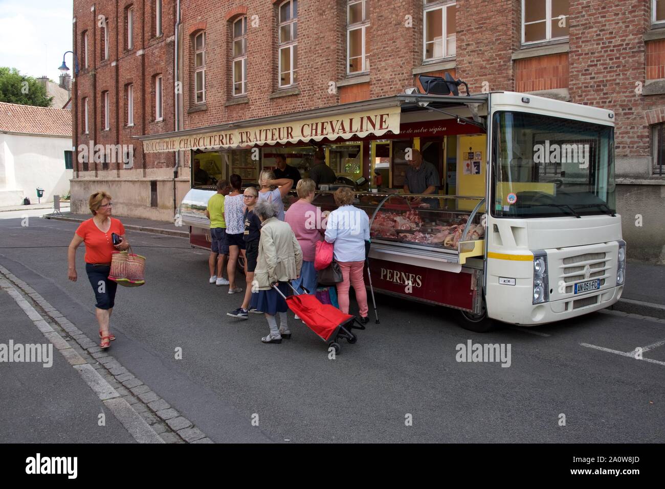 Die Kunden warten darauf, in einem mobilen Metzgerstand auf einem französischen Markt bedient zu werden Stockfoto