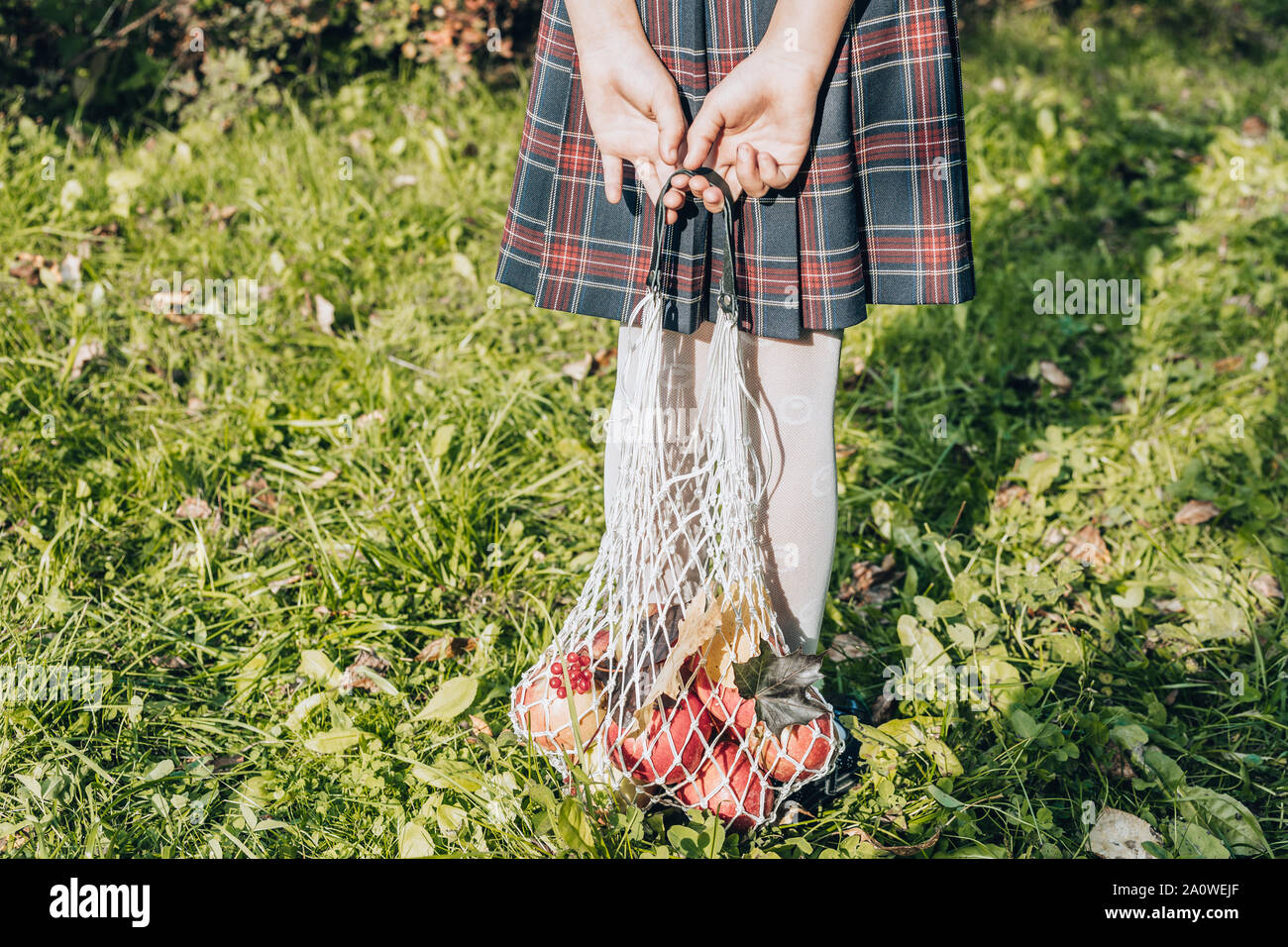 Mädchen in einem karierten Rock halten Sie eine Shopping Baumwolle string Beutel mit roten Äpfeln. Herbst Null Abfall Konzept Stockfoto