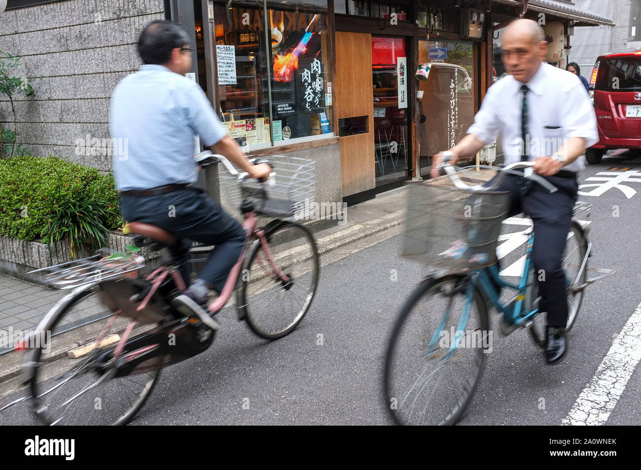 Männer auf dem Fahrrad in einer Straße von Kyoto in Japan. Stockfoto
