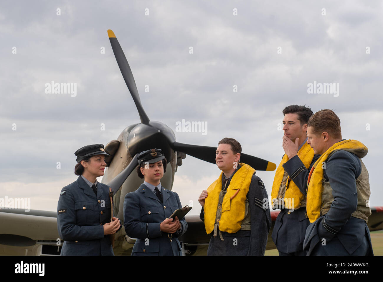Mitglieder der historischen Reenactment Gruppe Geist von Großbritannien stehen durch eine Hawker Hurricane auf der Flightline während des Duxford die Schlacht um England Air Show im Imperial War Museum in Duxford, Cambridgeshire. Stockfoto