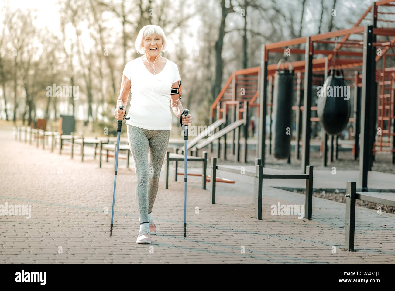 Gut - Ansprechende energische Frau fröhlich genießen Nordic walking Outdoor Stockfoto