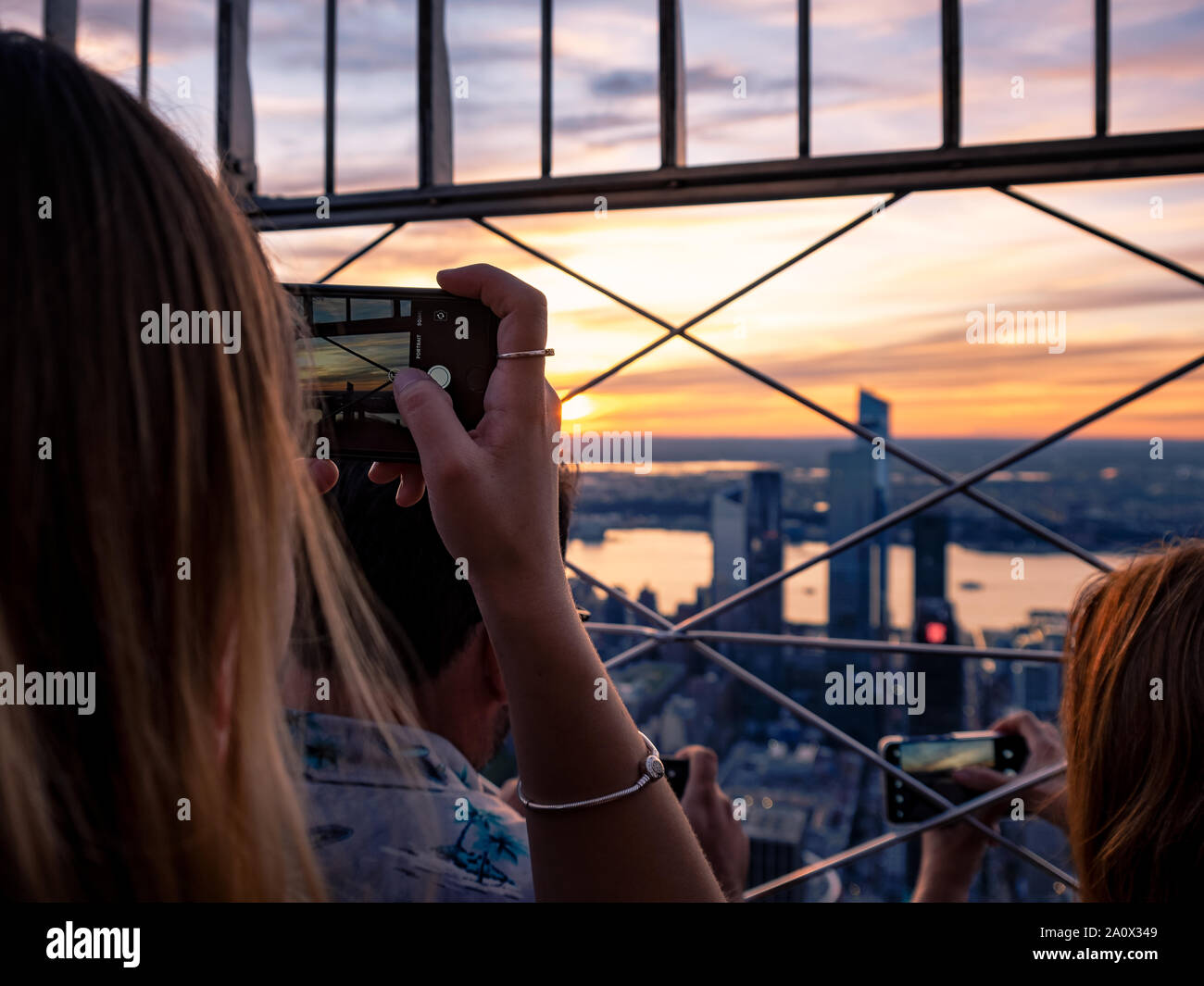 Junge Mädchen mit ihren Telefonen und Kameras Bilder der Skyline der Stadt von der Aussichtsplattform des Empire State Building, New York, US zu nehmen Stockfoto