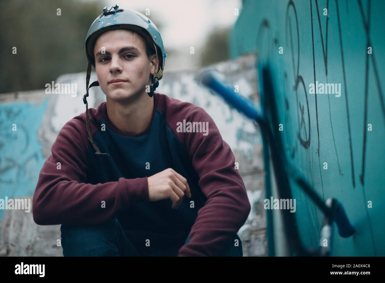 Professionelle junge Sportler Radfahrer Porträt mit BMX-Rad und Helm an Skatepark mit bmx Graffiti Stockfoto