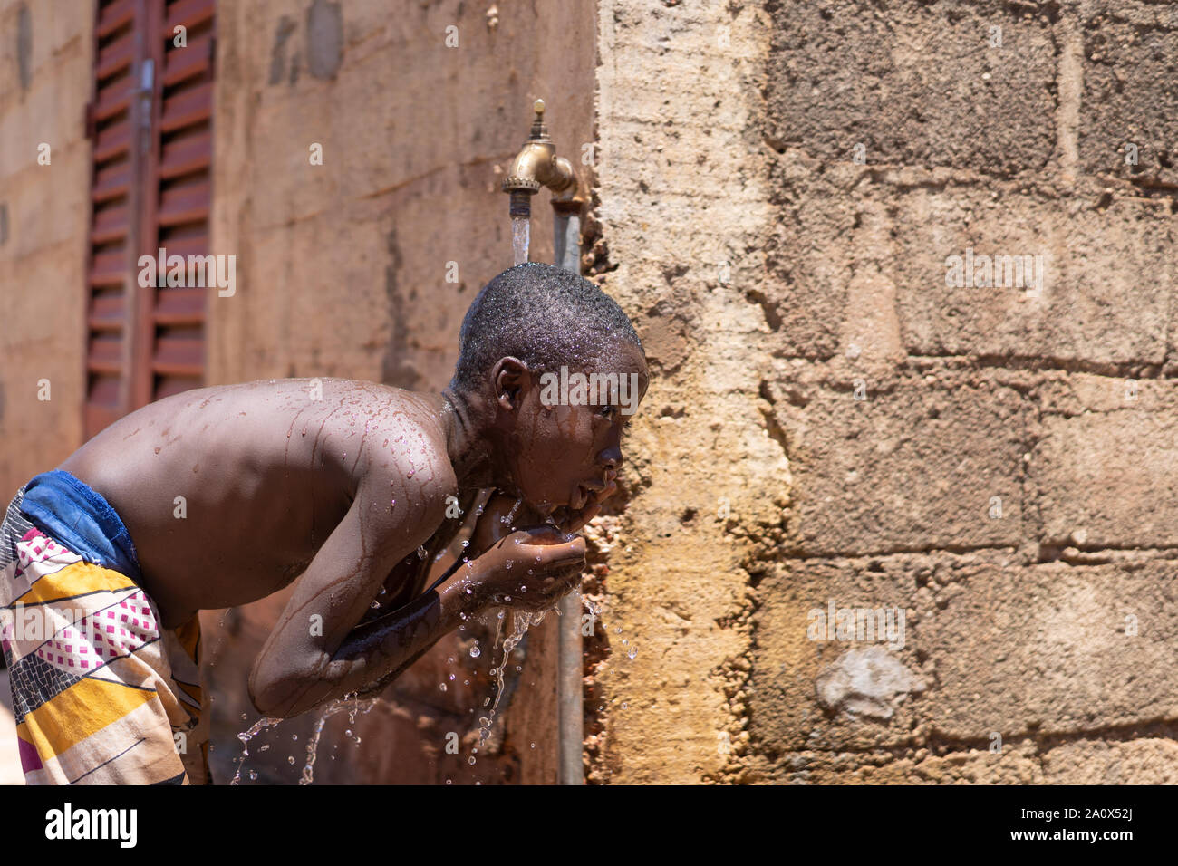 Afrikanisches Kind wäscht sich unter Leitungswasser Stockfoto