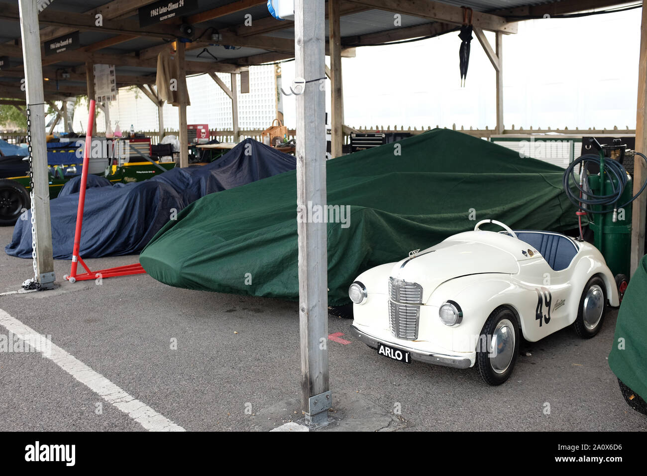 September 2019 - Classic Austin J40 Pedalwagen neben einem überdachten Rennwagen beim Goodwood Revival Race Meeting Stockfoto