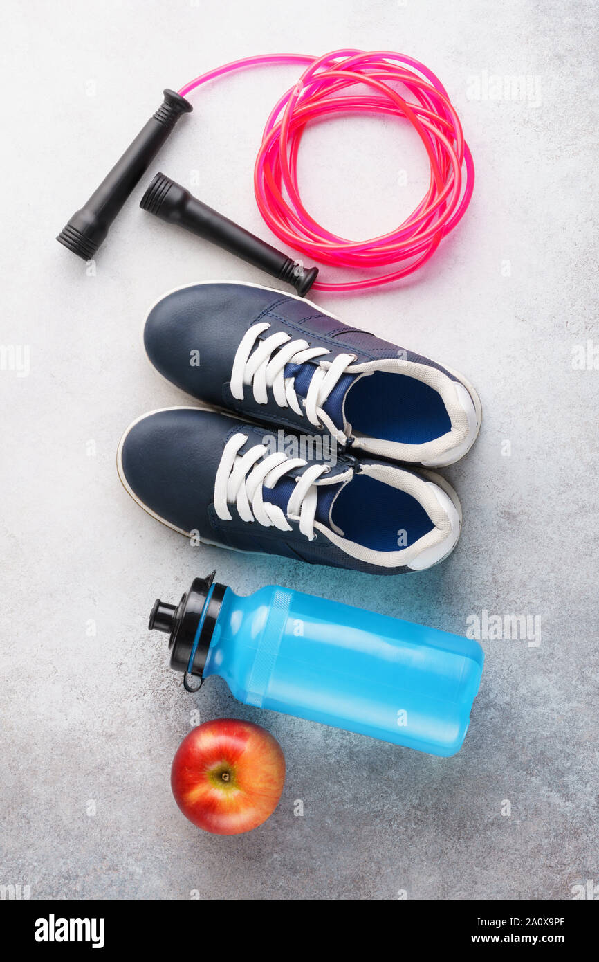 Fitness Hintergrund mit Turnschuhen, Wasserflasche und Springseil. Sportausrüstungen. Gesunder Lebensstil Konzept. Stockfoto