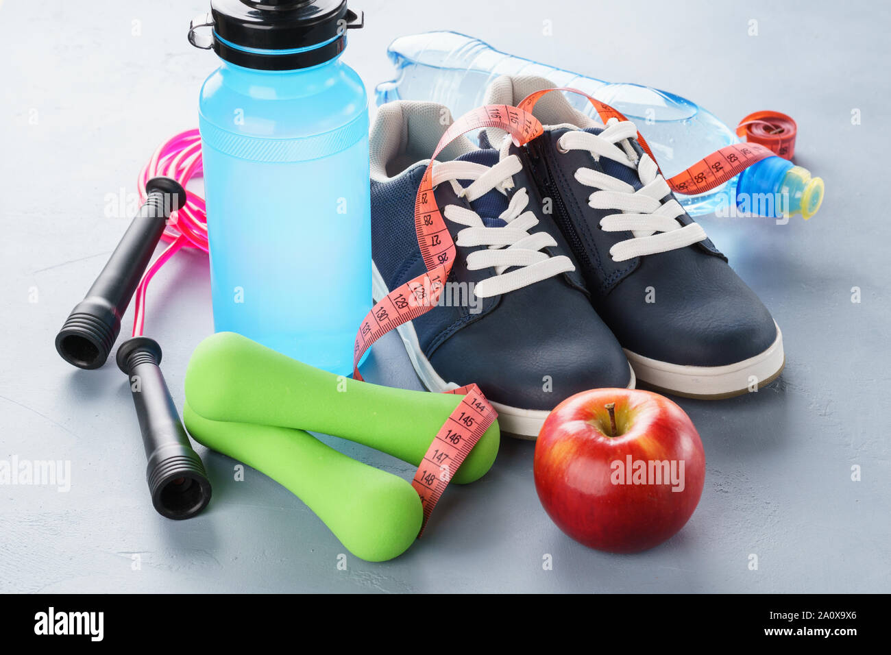 Satz von verschiedenen Sportartikel - Sneakers, Kurzhanteln, Wasserflasche und Springseil. Fitnessgeräte für Gym oder zu Hause. Gesunder Lebensstil Konzept. Stockfoto
